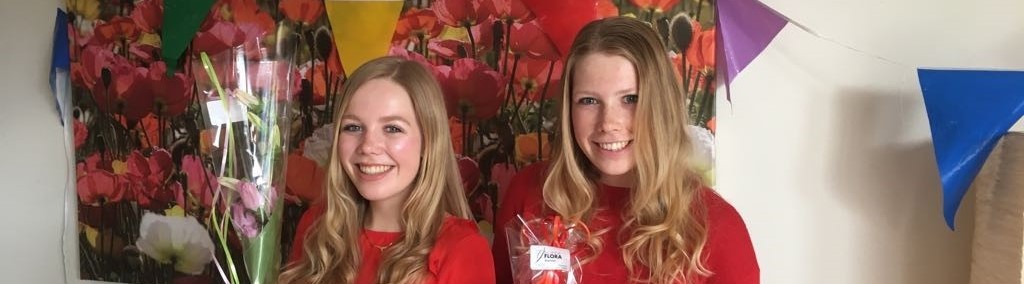 Nynke en haar zusje met bloemen in hun handen omdat ze beide net zijn afgestudeerd